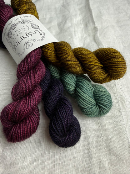 Bundle of 4 mini skeins of yarn labelled Inspiring Yarns on a white fabric background