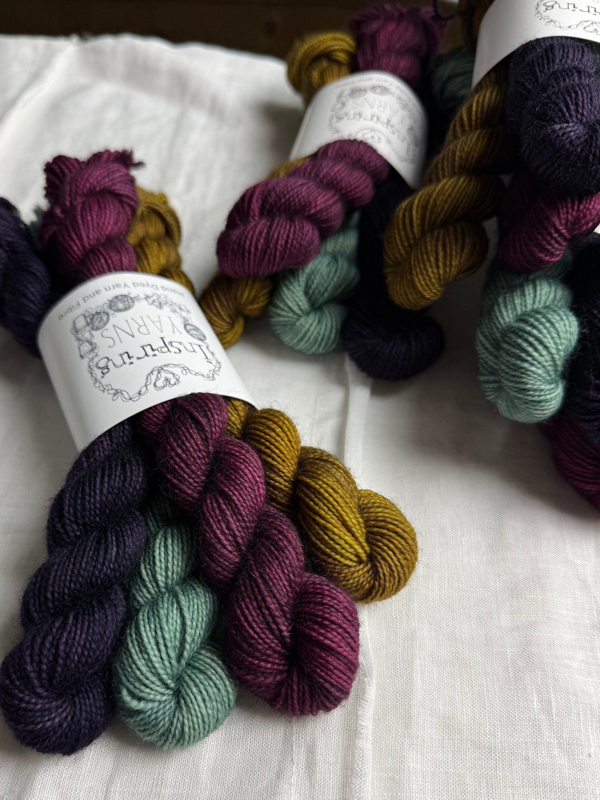 Bundles of colourful yarn labelled Inspiring Yarns on a white fabric background