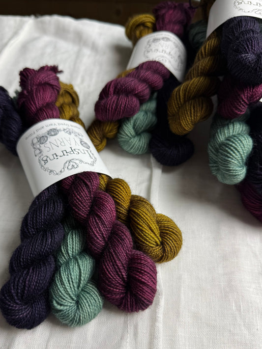 Bundles of colourful yarn labelled Inspiring Yarns on a white fabric background