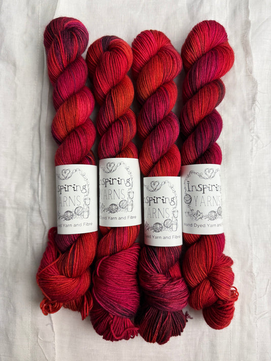 Four skeins of red variegated yarn labelled Inspiring Yarns on a white background