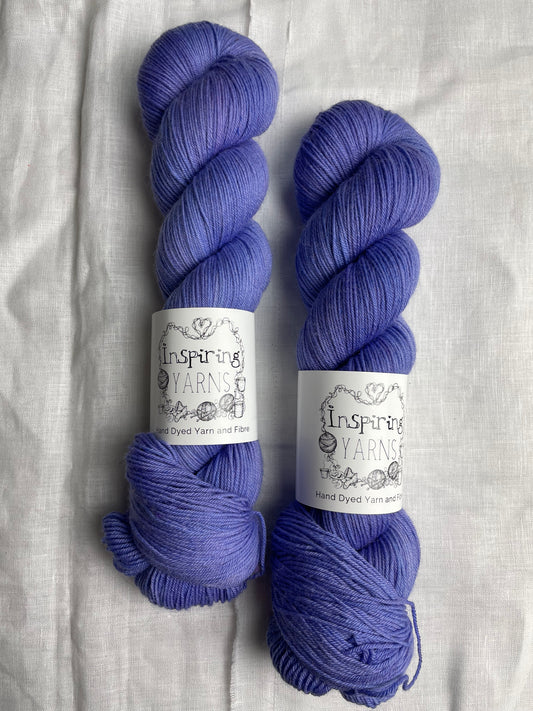 Two skeins of Moonstone, blue lilac coloured Merino Smooth Sock labelled Inspiring Yarns on a white linen background. 