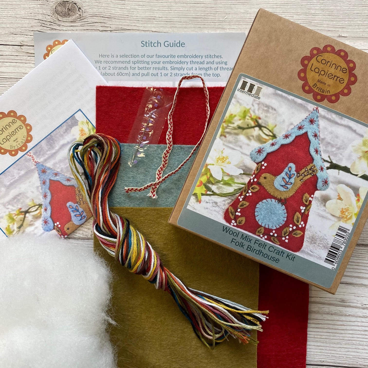 opened embroidery kit with threads, felt instructions, needle, stuffing and ribbon.