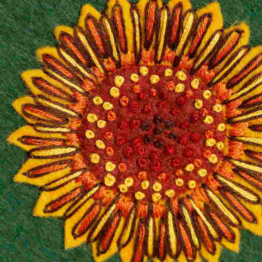 Embroidered sunflower design on a green fabric background