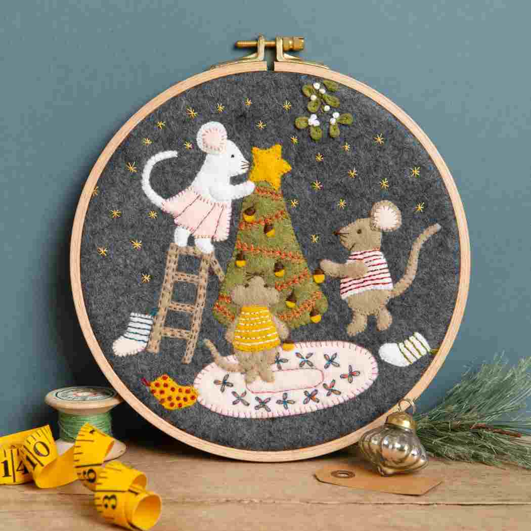 Embroidery hoop with embroidered scene of mice around a Christmas tree..