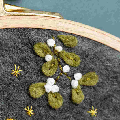 Close up of an embroidery hoop with embroidered felt mistletoe