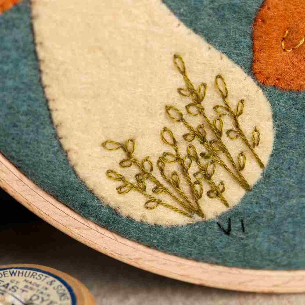 Close up of an embroidery hoop with green leaf pattern stitches