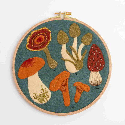 Embroidery hoop with colorful mushroom design on a blue background