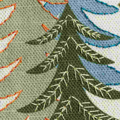 Close up of fir tree design on a linen fabric background with hand embroidered embellishments