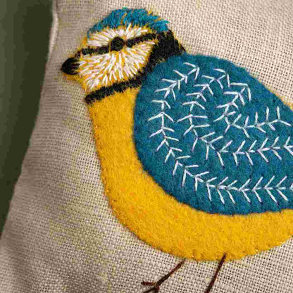 Embroidered bird design on fabric with a blue and yellow colour scheme.