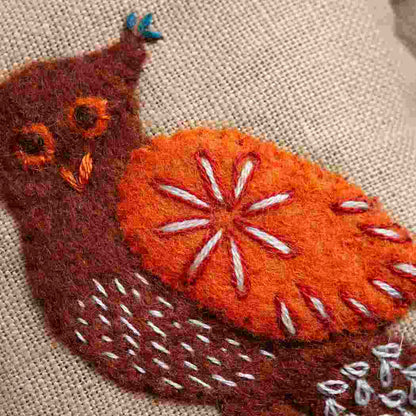 embroidered felt owl with an orange wing with stitched details.