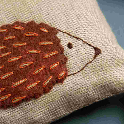 up close of brown hedgehog with stitched details on natural beige background. 