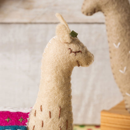 Close-up of a beige felt llama toy with a blurred background