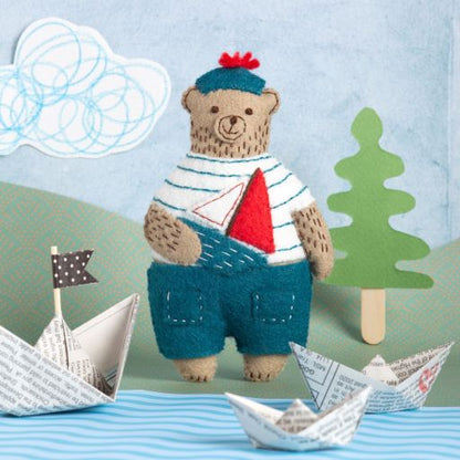 decorative felt bear in a sailors attire holding a toy boat.