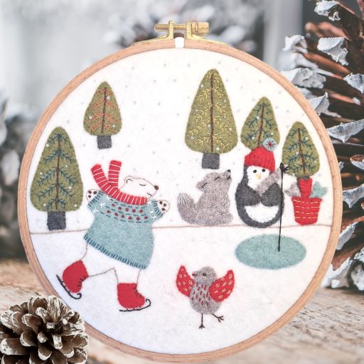 Embroidery hoop with a felt and embroidered winter design featuring animals skating & fishing on a frozen lake.  
