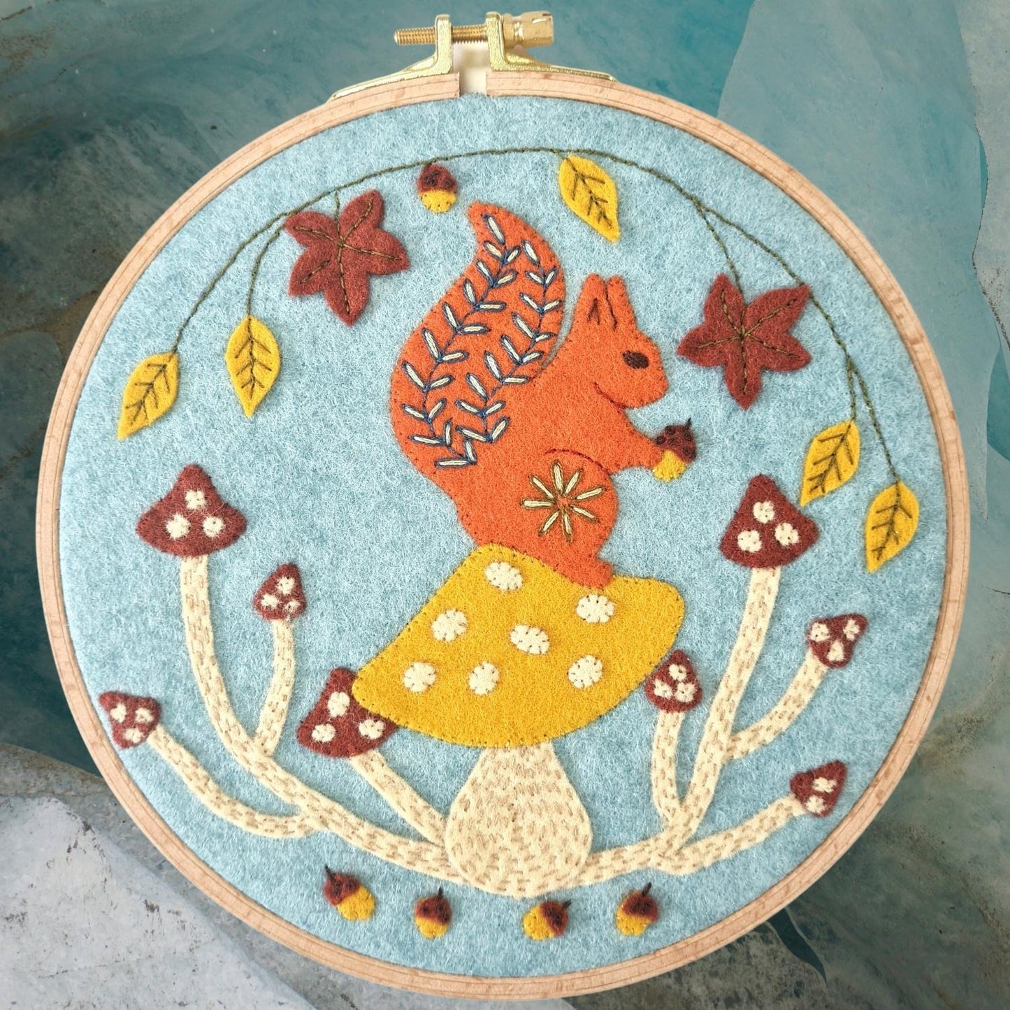 Embroidery hoop with a colorful squirrel design on a blue background