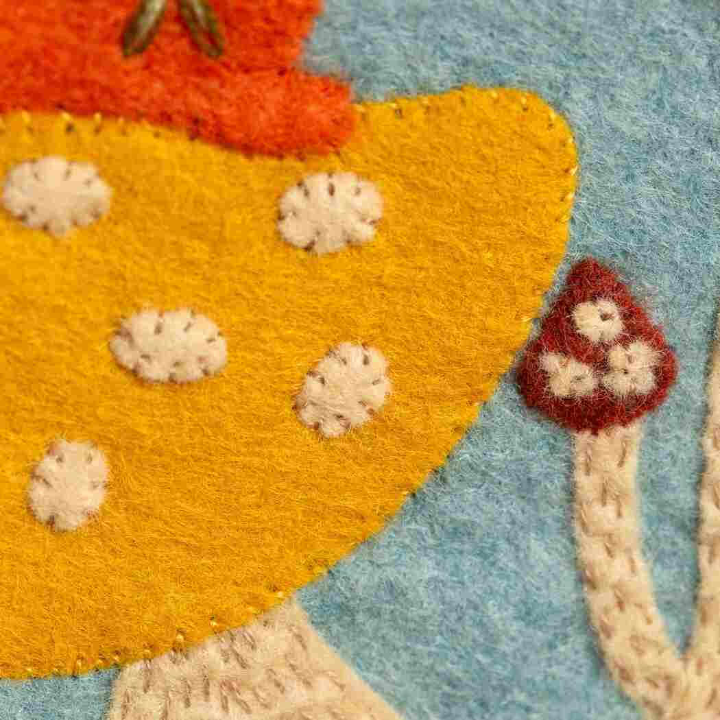 Close-up of a blue felt fabric surface with a yellow & red toadstool
