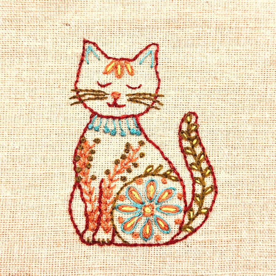 embroidered cat wit red outline and floral embellishment 