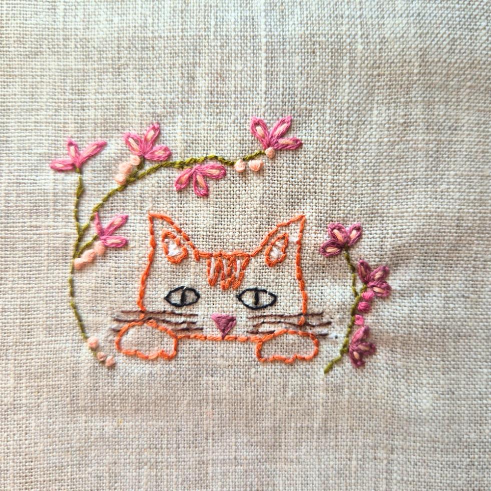 ginger cat head embroidery with embroidered florals surrounding it.