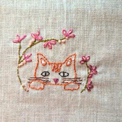 ginger cat head embroidery with embroidered florals surrounding it.