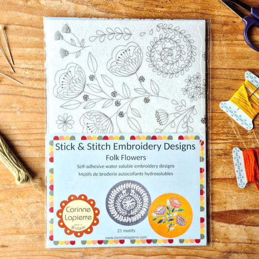 Booklet of Stick & Stitch Embroidery Designs on a wooden surface with embroidery tools.