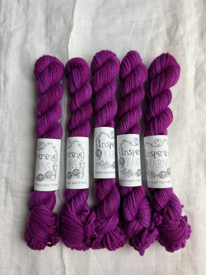 Five skeins of fuchsia tonal yarn labelled Inspiring Yarns on a white background