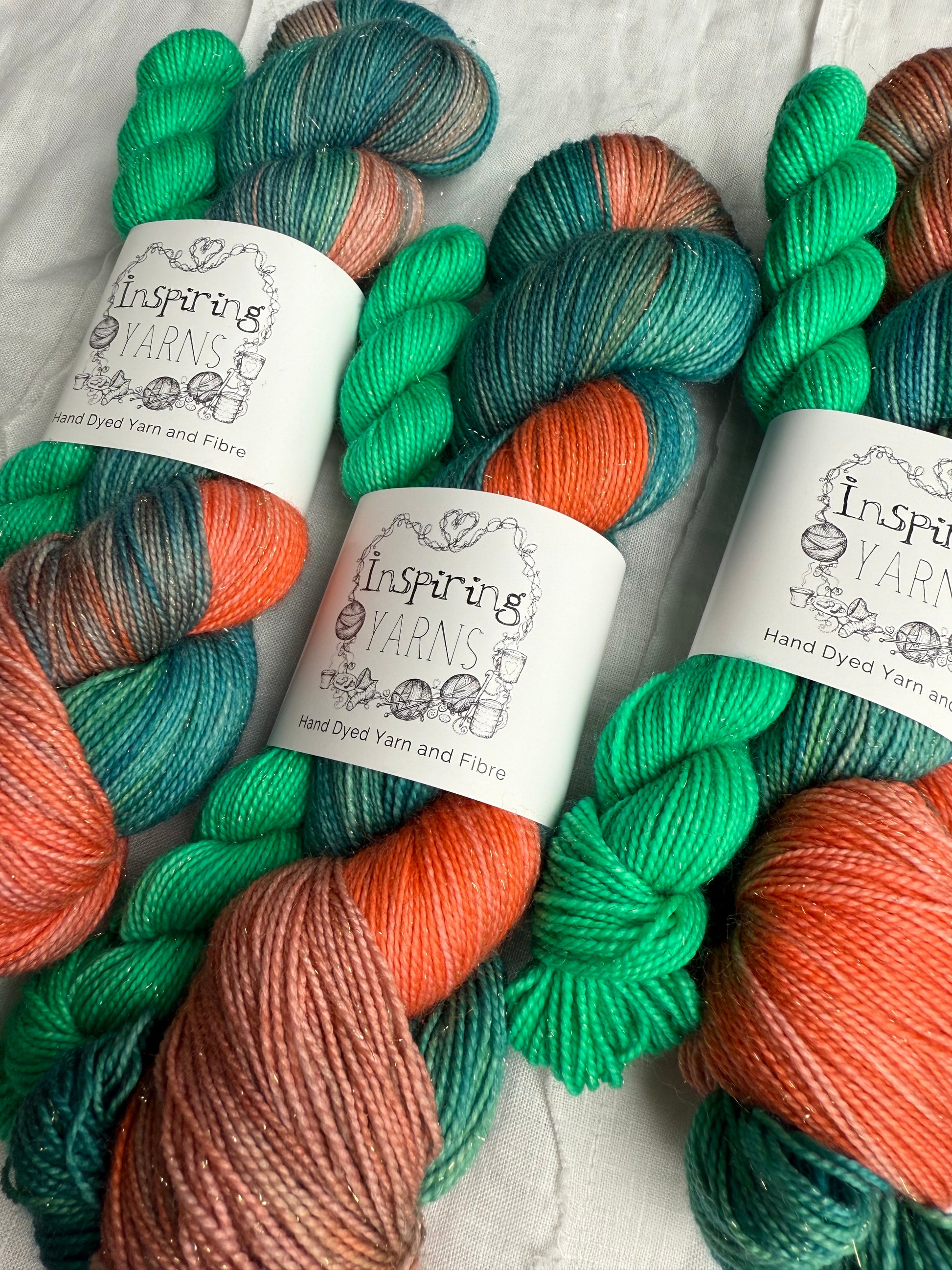 Colorful yarn skeins with 'Inspiring Yarns' labels on a textured surface