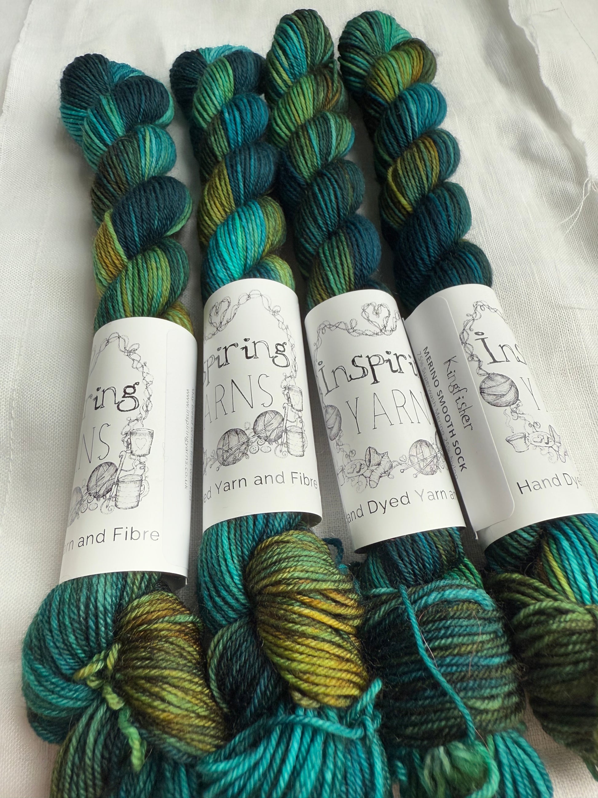 skeins of variegated yarn with teals and rusty orange with inspiring yarns labels on a white background 