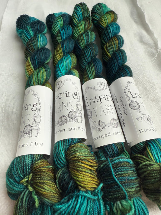 skeins of variegated yarn with teals and rusty orange with inspiring yarns labels on a white background 