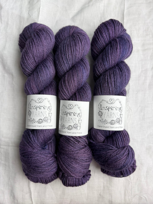 Three skeins of purple tonal yarn labelled Inspiring Yarns on a white background