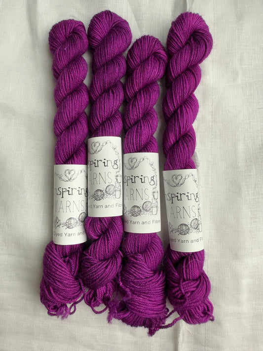 4 mini skeins of tonal fuchsia pink with inspiring yarns labels on a white background.