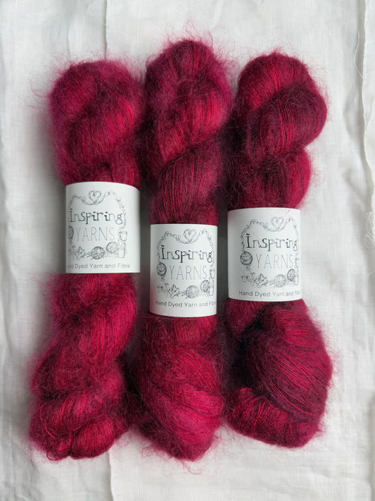 3 skeins of fluffy mohair in dark ruby red with white background and inspiring yarns label 