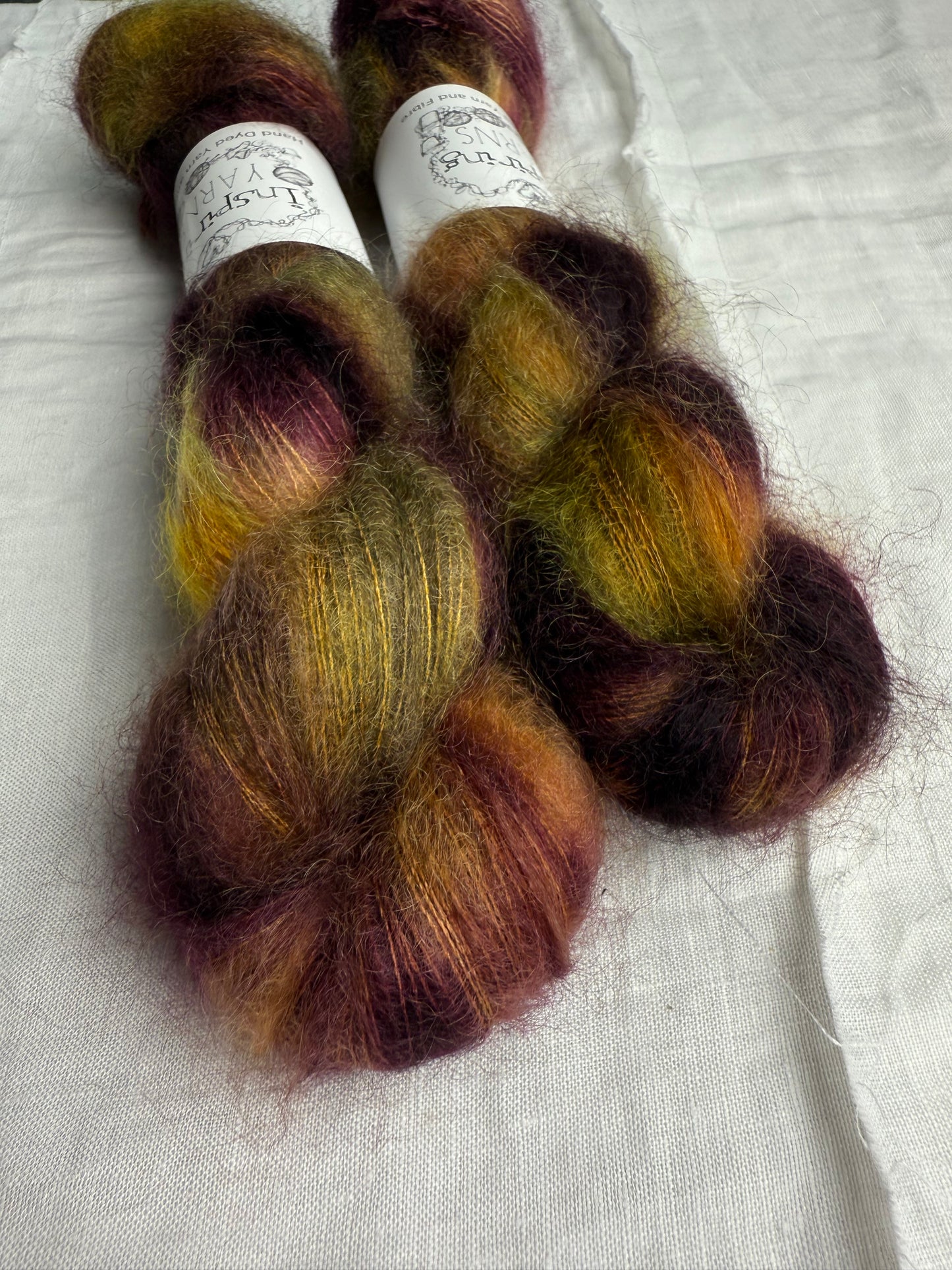 Two skeins of multicolored yarn on a white fabric background