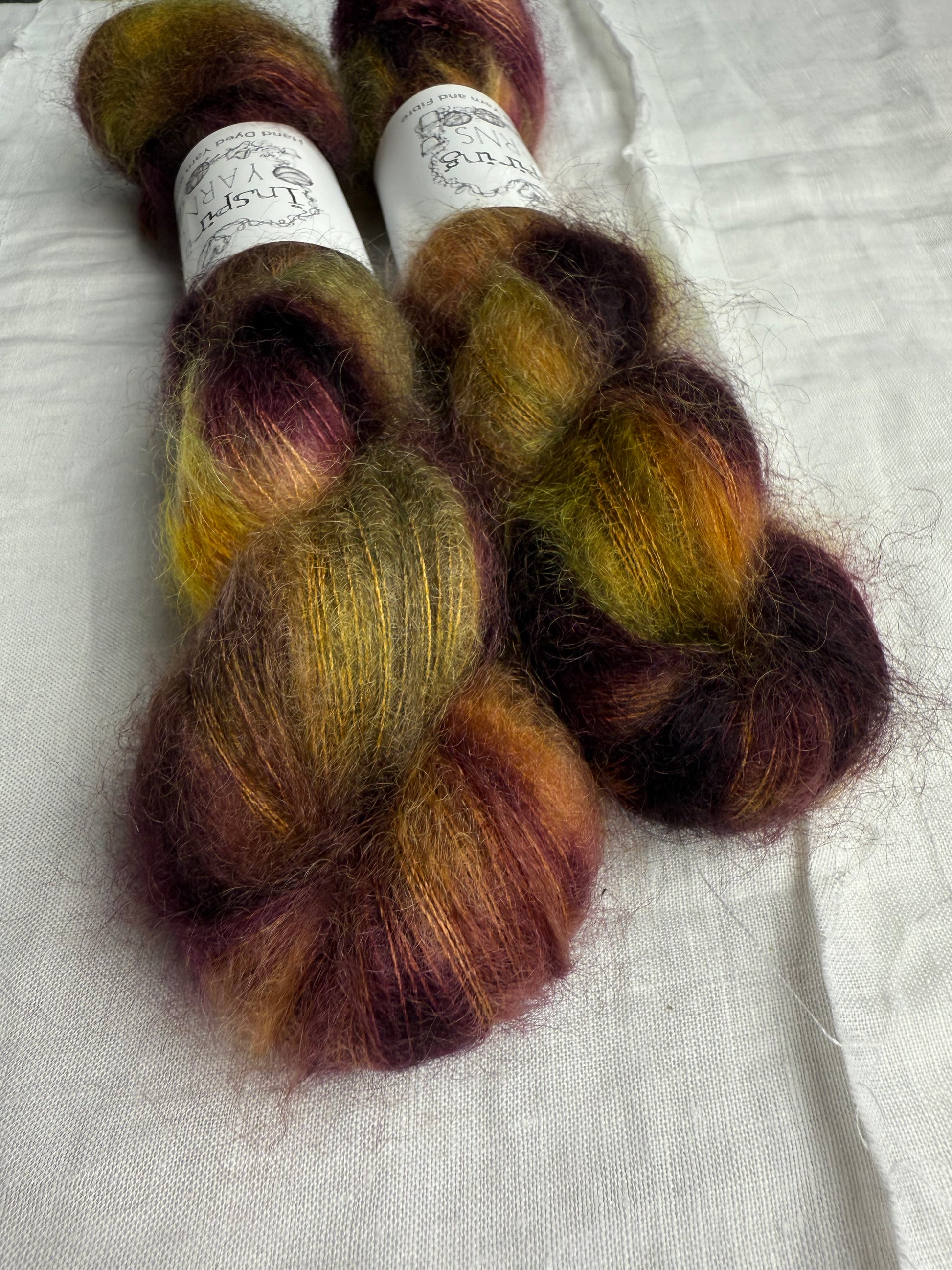 Two skeins of multicolored yarn on a white fabric background