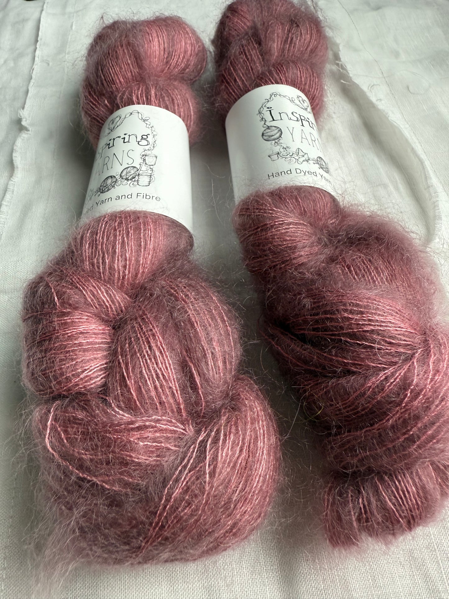 three skeins of dusty pink yarn with white inspiring yarns labels