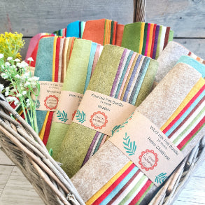 colourful wool felt bundles in a hamper with some wildflowers placed around them .