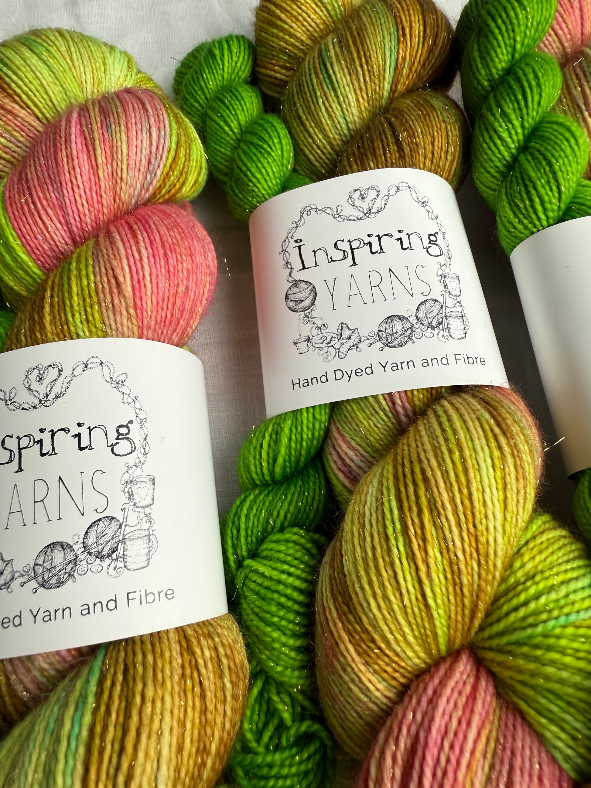 up close image of colourful skein of yarn with inspiring yarns labels on a white fabric background.  