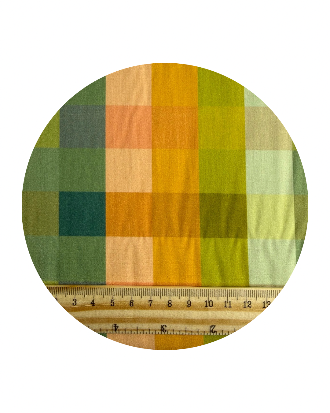 A round swatch of Colour Blocks Matcha from Slow Summer Collection for Art Gallery Fabrics, with a wooden ruler in centirmeters for scale, on a white background.