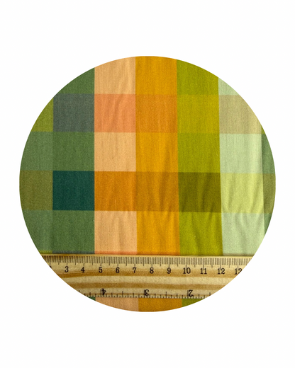 A round swatch of Colour Blocks Matcha from Slow Summer Collection for Art Gallery Fabrics, with a wooden ruler in centirmeters for scale, on a white background.
