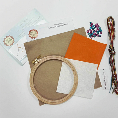 Embroidery hoop with fabric samples and sewing supplies on a white background