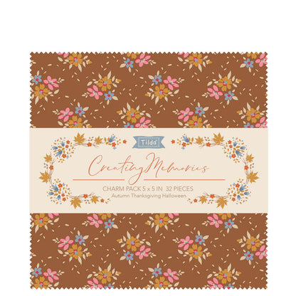 A fabric charm pack of 5" x 5" squares by Tilda  with an autumn colour theme of browns, blues and pinks in a small print, photographed against a white background.