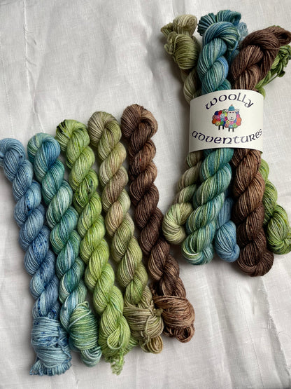 2 sets of mini skeins in blue green brown fade by Woolly Adventures on a white background