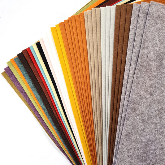 Collection of wool mix felt in an array of colours on a white surface.