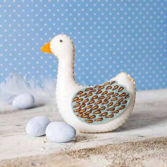 decorative felt goose on wooden surface with blue polka dote background.
