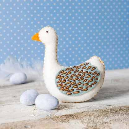 decorative felt goose on wooden surface with blue polka dote background.