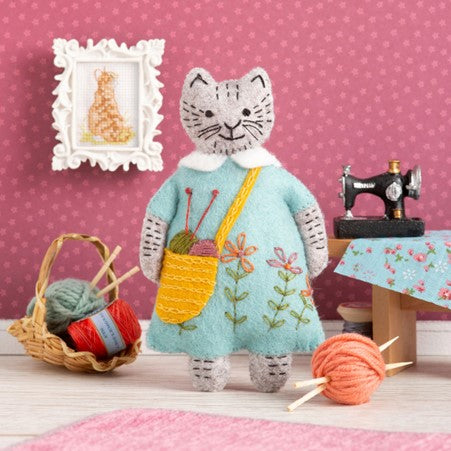 greeting card with image of felt cat with knitting accessories and polka dot backdrop.  