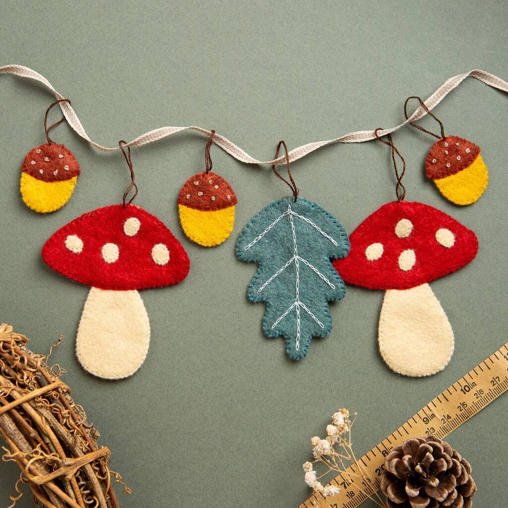 Decorative string with felt toadstools, acorns, and leaves on a green background. 